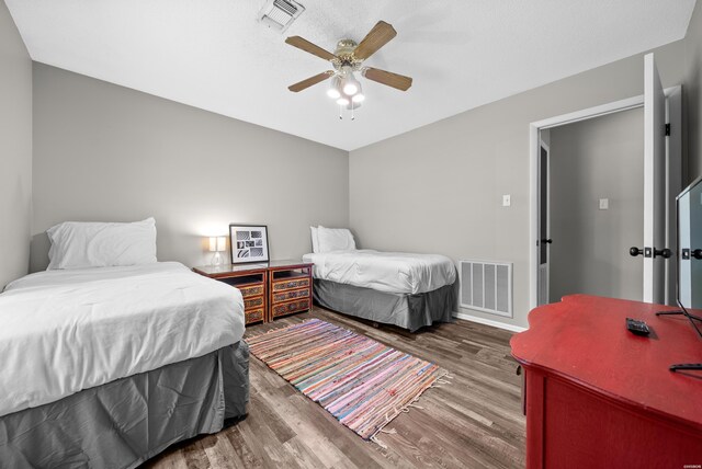 bedroom featuring baseboards, ceiling fan, visible vents, and wood finished floors