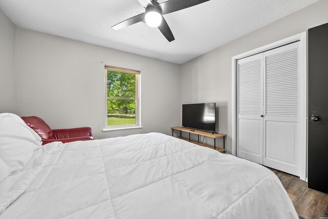 bedroom featuring a textured ceiling, a ceiling fan, dark wood finished floors, and a closet