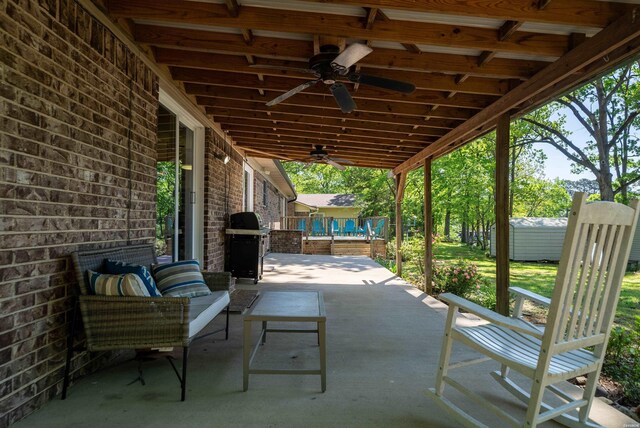 view of patio with a storage shed, area for grilling, ceiling fan, an outbuilding, and an outdoor living space