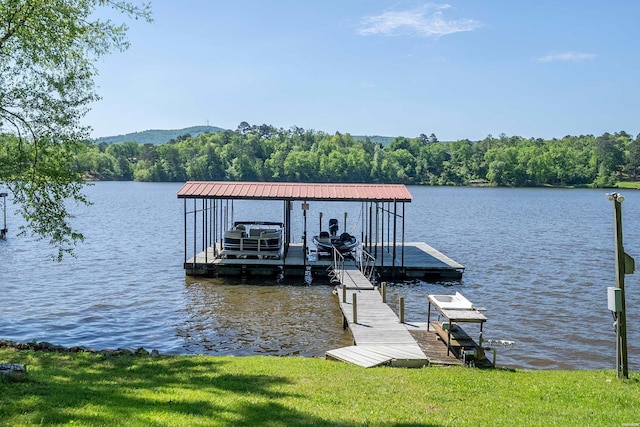 view of dock with a water view, boat lift, and a wooded view