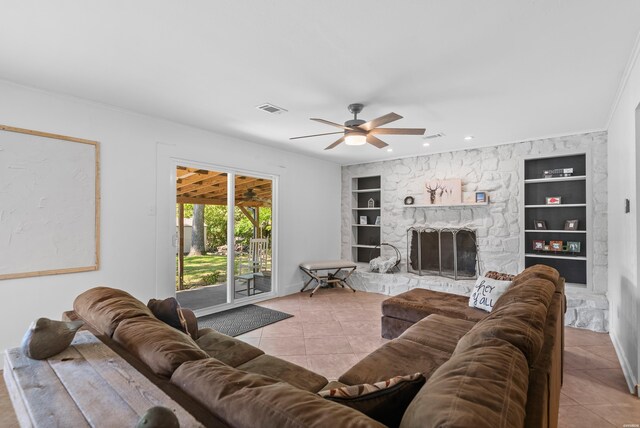 living area featuring light tile patterned floors, visible vents, ceiling fan, built in shelves, and a fireplace