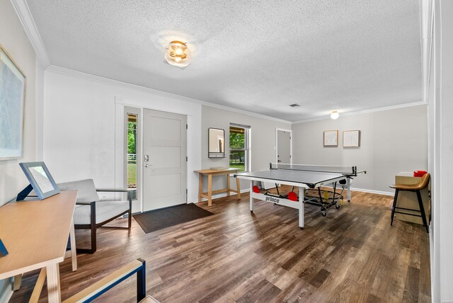 game room with dark wood-style floors, crown molding, a textured ceiling, and baseboards