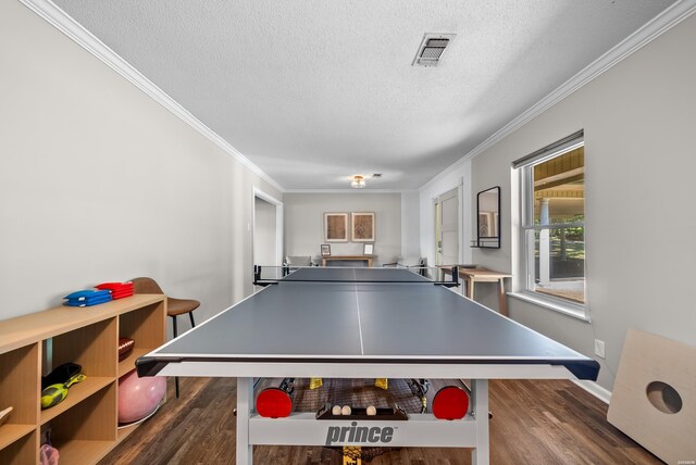 game room featuring a textured ceiling, visible vents, dark wood-style flooring, and ornamental molding