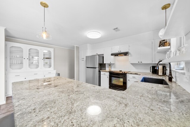 kitchen with black range with electric stovetop, a sink, white cabinets, freestanding refrigerator, and pendant lighting