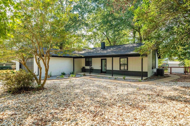 view of front of property with a patio area, fence, central AC unit, and brick siding