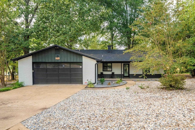 mid-century inspired home featuring driveway, an attached garage, a chimney, and brick siding