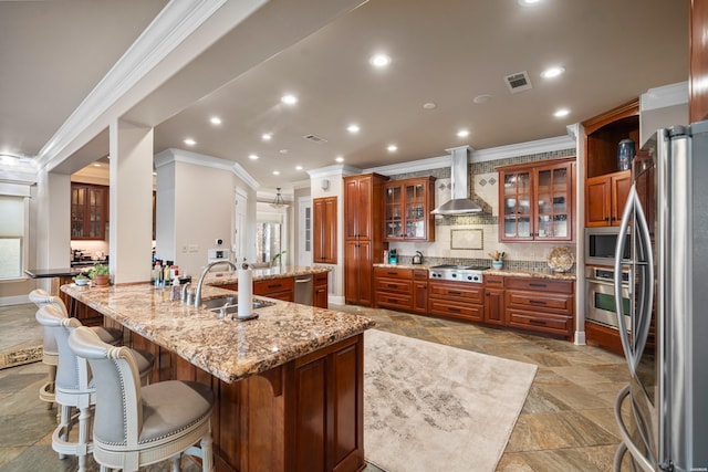 347 Paradise Pt, Hot Springs, AR 71913 - kitchen featuring wall chimney range hood, appliances with stainless steel finishes, ornamental molding, brown cabinetry, and a kitchen bar