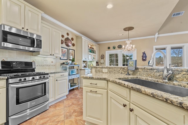 kitchen featuring a notable chandelier, a sink, backsplash, appliances with stainless steel finishes, and crown molding