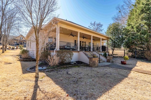 back of property featuring stucco siding, ceiling fan, and fence