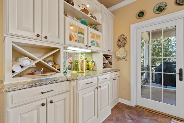 kitchen featuring light stone counters, glass insert cabinets, backsplash, and ornamental molding