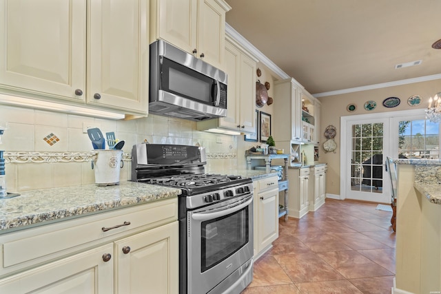 kitchen featuring tasteful backsplash, cream cabinetry, appliances with stainless steel finishes, and visible vents