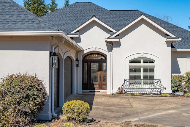 entrance to property featuring stucco siding, roof with shingles, and french doors