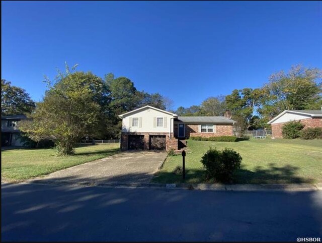 split level home featuring a garage, concrete driveway, and a front yard