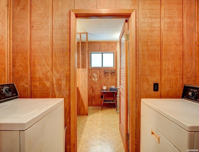 washroom featuring wooden walls, washing machine and clothes dryer, and laundry area