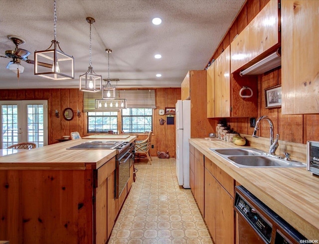 kitchen with dishwasher, a sink, butcher block counters, freestanding refrigerator, and a center island