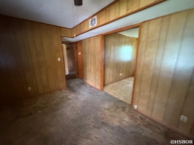501 N Byrd St, Crossett, AR 71635 - empty room featuring carpet, wood walls, and a ceiling fan