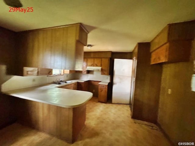 501 N Byrd St, Crossett, AR 71635 - kitchen with a peninsula, brown cabinets, under cabinet range hood, light countertops, and a sink