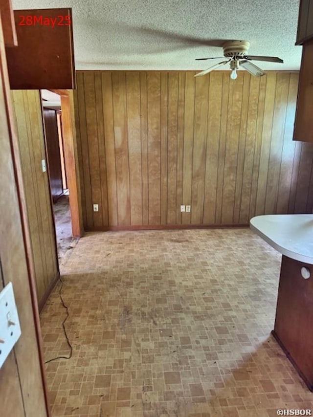 501 N Byrd St, Crossett, AR 71635 - unfurnished dining area featuring a ceiling fan, wood walls, brick patterned floors, and a textured ceiling