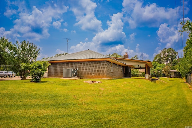 114 Roy Cir, Monticello, AR 71655 - back of property with a lawn, ceiling fan, central air condition unit, a chimney, and brick siding