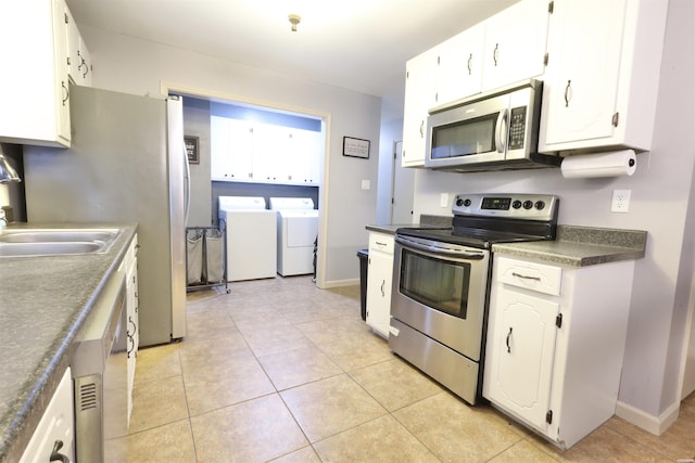 kitchen with dark countertops, appliances with stainless steel finishes, white cabinets, and washing machine and clothes dryer