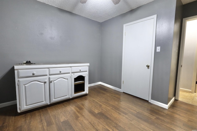 interior space featuring a textured ceiling, dark wood finished floors, a ceiling fan, and baseboards