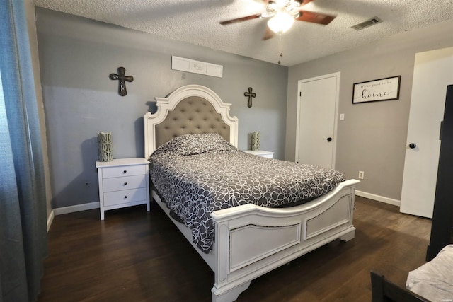 bedroom featuring baseboards, visible vents, dark wood finished floors, and a textured ceiling