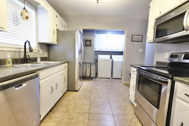 kitchen with stainless steel appliances, washer and clothes dryer, dark countertops, and a sink