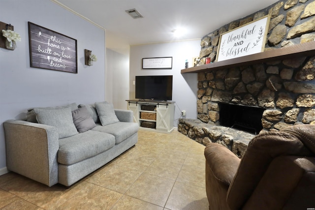 living area featuring a stone fireplace, light tile patterned flooring, and visible vents