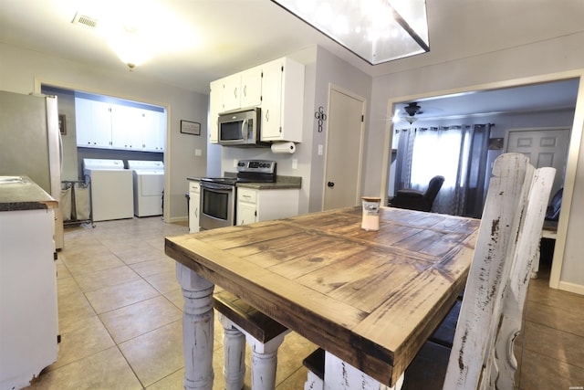 dining room with light tile patterned floors, washing machine and clothes dryer, visible vents, and baseboards