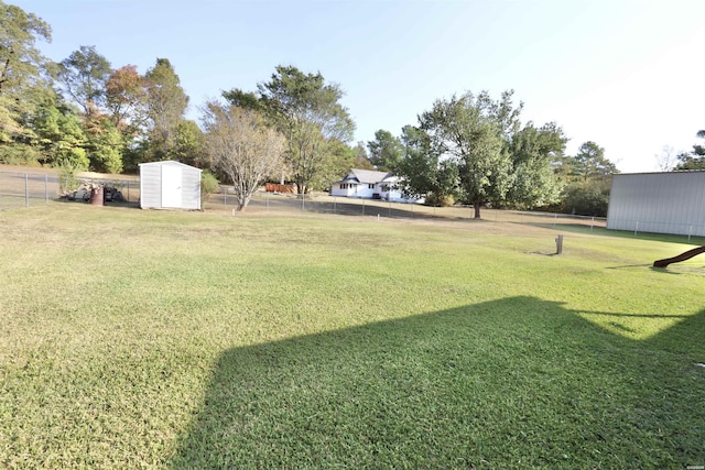 view of yard featuring an outbuilding, fence, and a storage shed