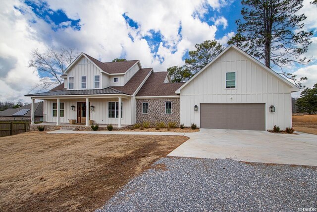 modern inspired farmhouse with a porch, board and batten siding, a standing seam roof, metal roof, and driveway