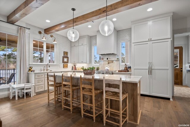 kitchen featuring a breakfast bar area, hanging light fixtures, white cabinets, a kitchen island, and paneled fridge