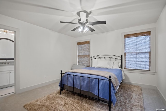 bedroom with light carpet, a sink, baseboards, and ensuite bathroom