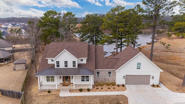 modern farmhouse with concrete driveway, a standing seam roof, fence, a porch, and board and batten siding