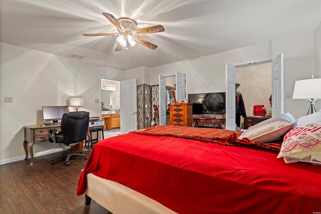 bedroom with baseboards, ensuite bath, ceiling fan, dark wood-style flooring, and a spacious closet