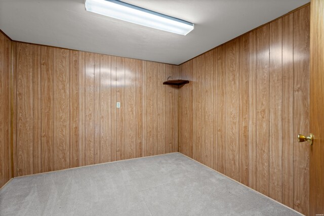 unfurnished room featuring light colored carpet and wooden walls