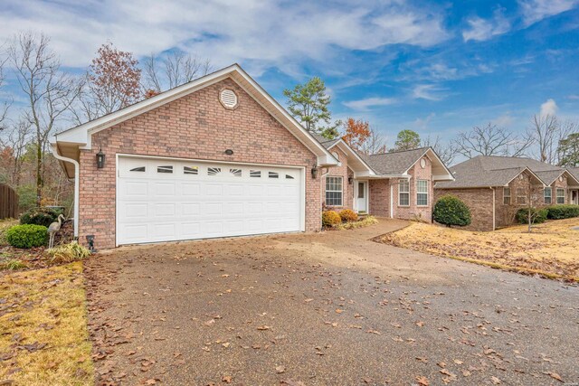 single story home with driveway, an attached garage, and brick siding