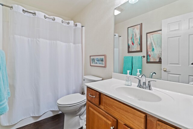 bathroom featuring toilet, wood finished floors, and vanity