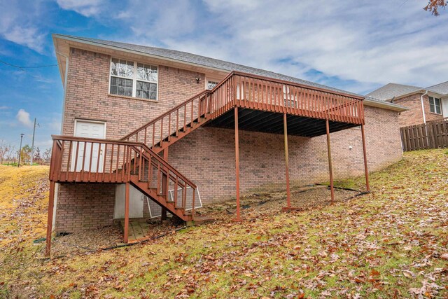 back of property featuring a deck, brick siding, fence, and stairway