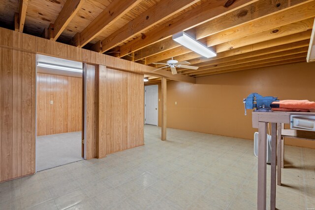 finished below grade area with ceiling fan, wooden walls, and tile patterned floors