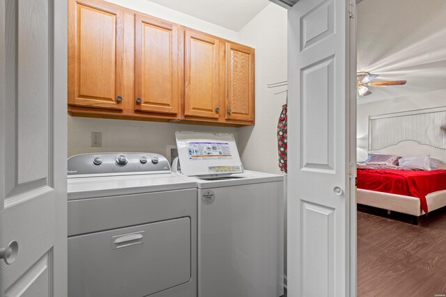 clothes washing area featuring separate washer and dryer, dark wood-type flooring, and cabinet space