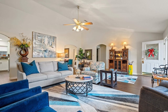 living room featuring baseboards, arched walkways, ceiling fan, wood finished floors, and high vaulted ceiling