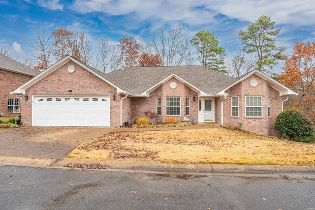 ranch-style house featuring driveway, an attached garage, a shingled roof, and brick siding