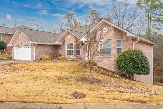 ranch-style home with a garage, driveway, a shingled roof, brick siding, and a front yard