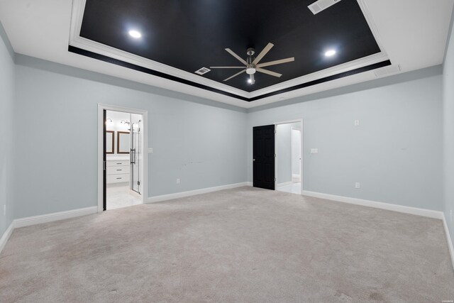 spare room featuring light carpet, a tray ceiling, a ceiling fan, and baseboards