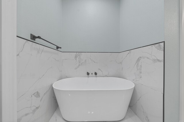 full bathroom featuring marble finish floor and a freestanding tub