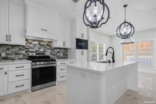 kitchen with stainless steel gas range, a center island with sink, marble finish floor, and light countertops