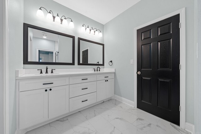 bathroom with double vanity, marble finish floor, baseboards, and a sink