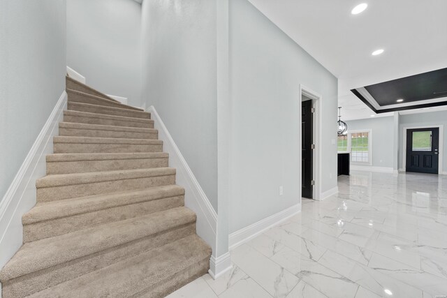 staircase with marble finish floor, recessed lighting, a raised ceiling, and baseboards