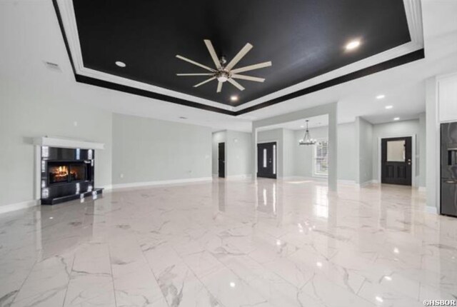 unfurnished living room with a glass covered fireplace, a raised ceiling, a notable chandelier, and baseboards